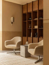 Two beige Harbour Lounge Chairs on a Tile Rug, styled with a Volume Side Table, Wing Wall Lamp, and a wooden bookshelf.